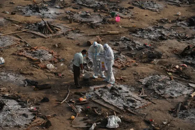 Relatives collect the remains of Covid victim after a mass cremation at a cremation ground in New Delhi