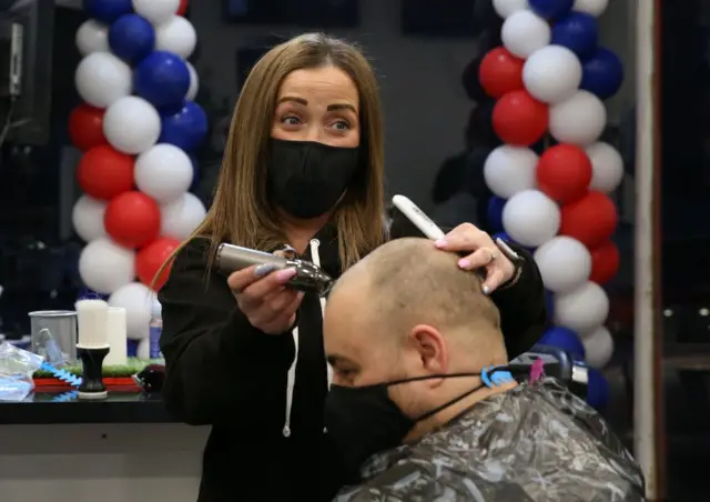 A barber shaves a man's head