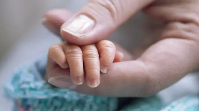 Mother holding newborn's hand