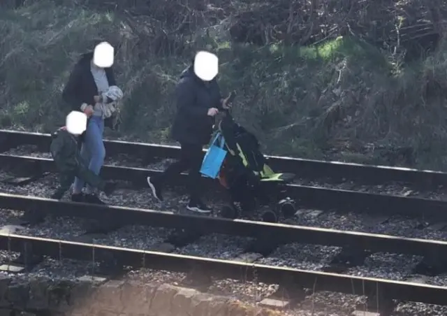 Adults and child on rail line