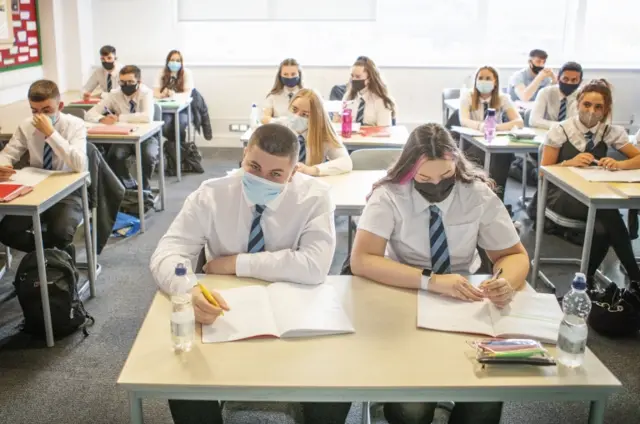 School pupils wearing face coverings sat at desks