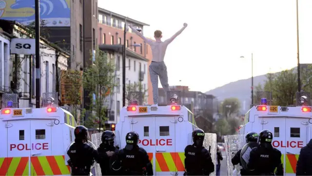 A rioter stands on a police Land Rover