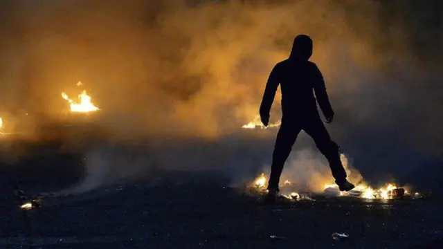 silhouette of rioter in the flames of a street fire in Belfast