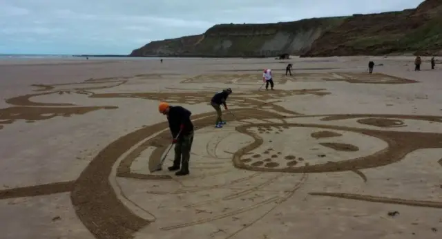 Artists creating the seal artwork on Cayton Bay.