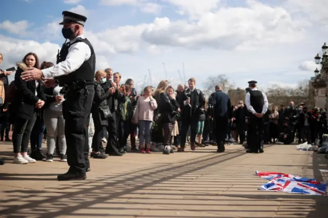 People stand in front of the public outside Buckingham Palace