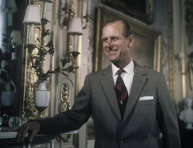 Prince Philip smiling in a suit and a black and red striped tie