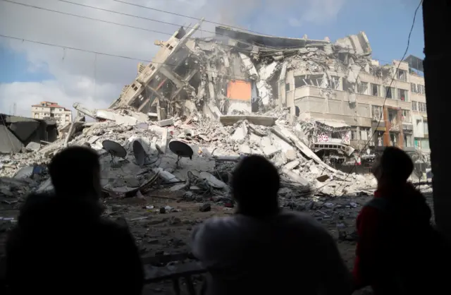 Palestinians look at the remains of a tower block which was destroyed by Israeli air strikes in Gaza City