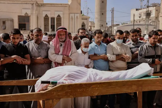 Mourners recite a prayer over the body of Majd Abu Saadahthe, a Palestinian killed in an Israeli airstrike, during his funeral in the town of Khan Yunis in the southern Gaza Strip