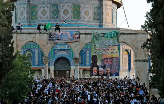 Palestinian worshippers raise the Hamas and the Palestinian flag in the al-Aqsa mosque in Jerusalem's Old City after Eid al-Fitr prayers