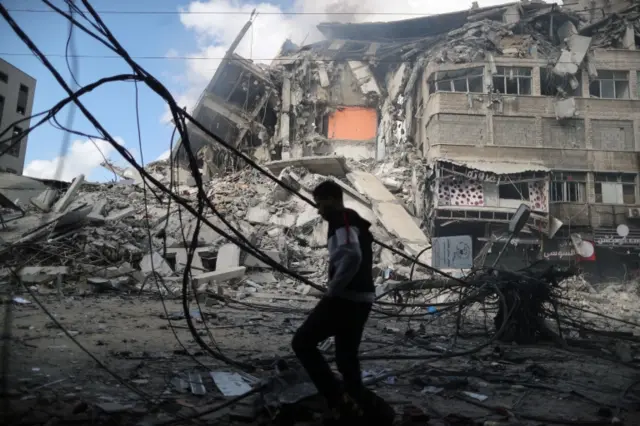 A Palestinian man walks past the remains of a tower building destroyed in Israeli air strikes. Photo: 13 May 2021