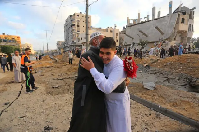 Palestinians celebrate Eid al-Fitr near ruins of buildings destroyed by ongoing Israeli airstrikes in Beit Lahia, Gaza