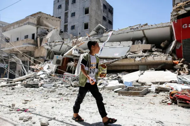 A Palestinian boy walks in front of a building which was destroyed in an Israeli airstrike on Gaza