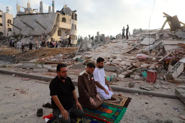 Palestinian Muslim men perform the morning Eid al-Fitr prayer outdoors amid the destruction in Gaza