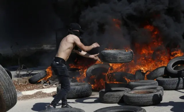 A Palestinian protester throws a tyre during clashes with Israeli troops at a checkpoint near the West Bank City of Jenin. Photo: 14 May 2021