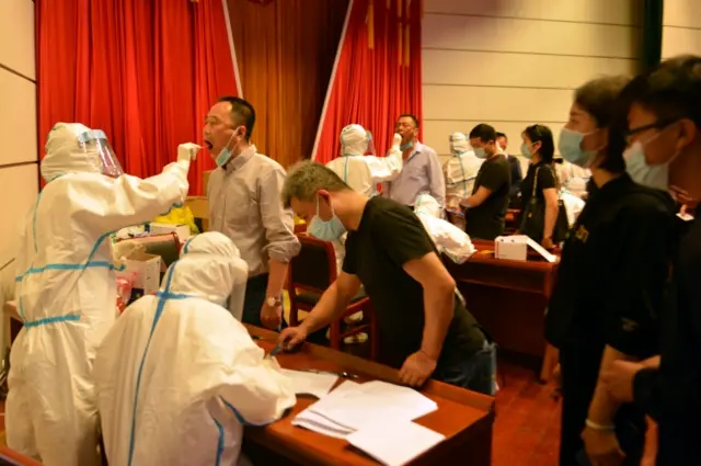 Medical workers collect swabs from residents following new cases of the coronavirus disease (COVID-19), at a nucleic acid test site in Luan