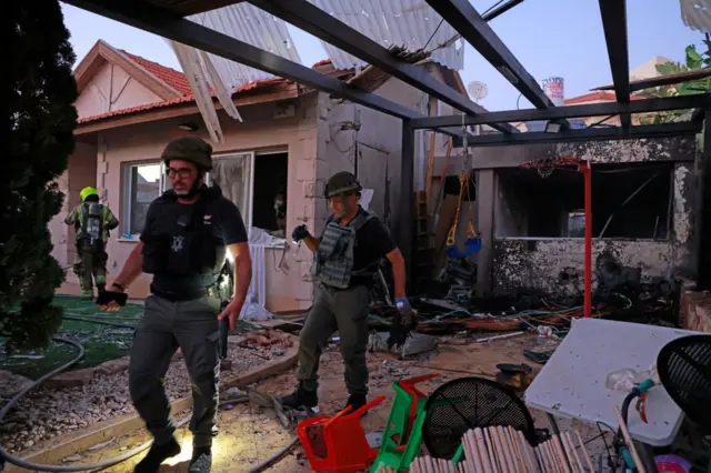 Israeli emergency services inspect a house hit by rocket fire in Ashkelon