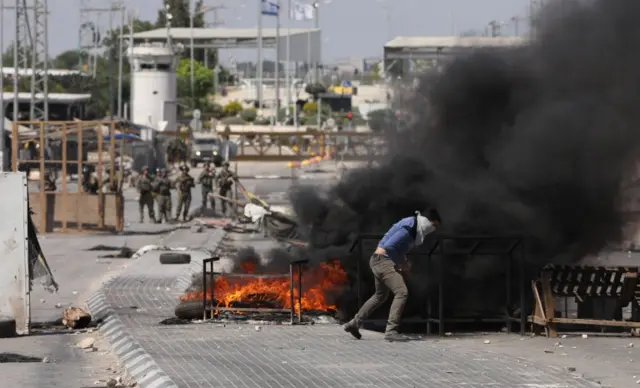 A Palestinian protester hurls stones during clashes with Israeli troops at a checkpoint near the West Bank City of Jenin. Photo: 14 May 2021