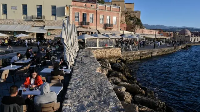 Local and tourist sit at terraces and walk through the old town of Chania (La Canee) in the north west of the island of Crete, on May 13, 2021