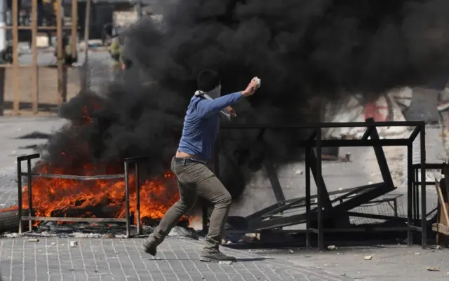 A Palestinian protester hurls stones during clashes with Israeli troops at checkpoint near the West Bank City of Jenin. Photo: 14 May 2021