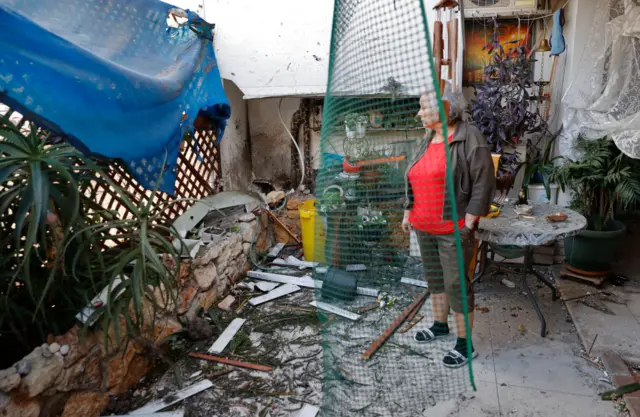 An Israeli woman checks the damage in her house hit by Palestinian rocket fire in the southern city of Ashkelon