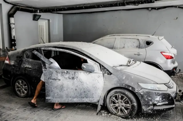 A man examines damaged cars in Ashkelon, Israel, after a rocket fire from Gaza. Photo: 14 May 2021