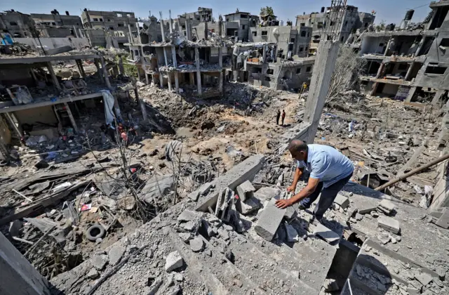 Palestinians assess the damage caused by Israeli air strikes, in Beit Hanun