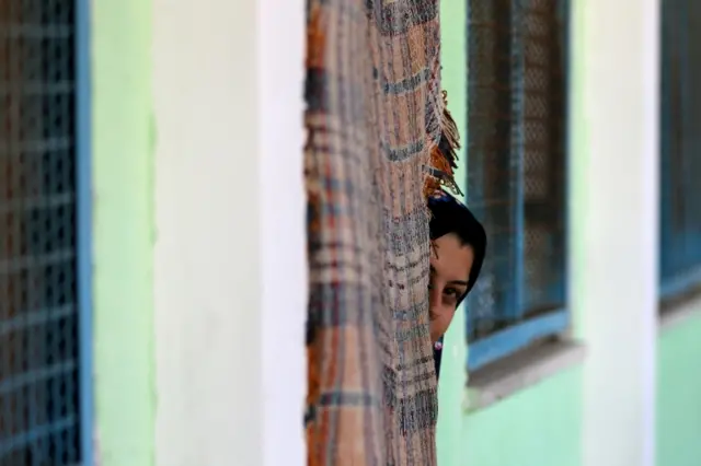 A Palestinian woman, who fled her home due to Israeli air and artillery strikes, looks out of a classroom at a United Nations-run school where she took refuge in Gaza City on 15 May 2021