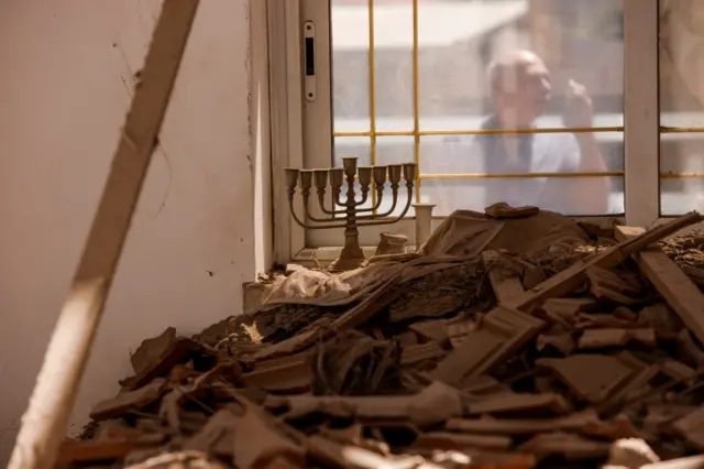 Yehushua El-Gazar uses his mobile phone outside his house that was damaged following a rocket fire from Gaza towards Israel in the city of Sderot, southern Israel, on 15 May 2021