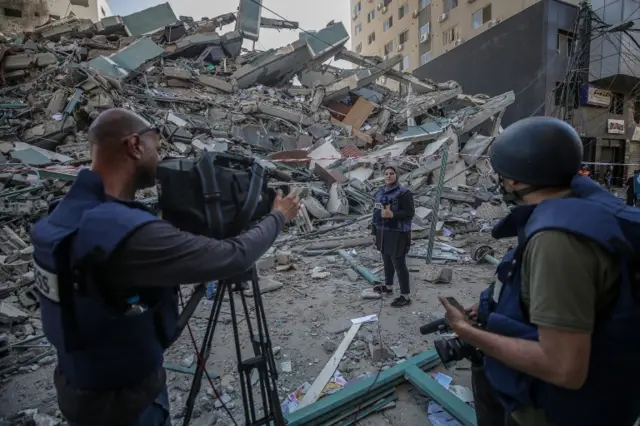 A Palestinian TV crew work next to rubbles of the tower block that housed several media outlets in Gaza City. Photo: 15 May 2021