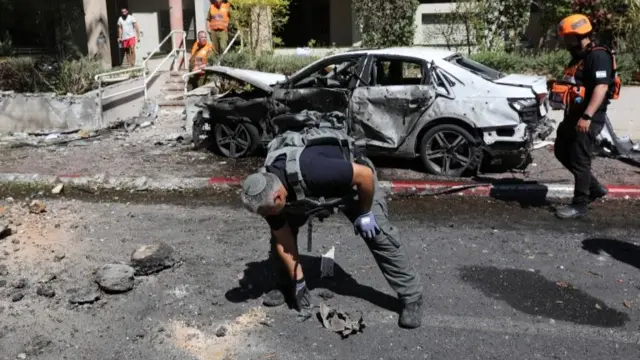 Israeli emergency teams and police inspect the scene where a rocket from the Gaza Strip hit the Israeli town of Ramat Gan, near Tel Aviv (15 May 2021)