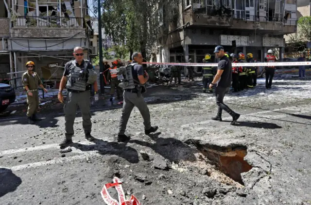 Members of Israeli security and emergency services work on a site hit by a rocket in Ramat Gan near the coastal city of Tel Aviv, on 15 May 2021