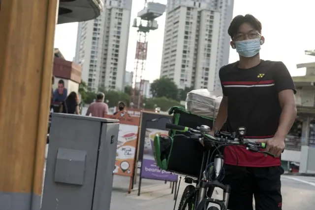 A food delivery rider pushes his bicycle through the Holland Village neighbourhood in Singapore