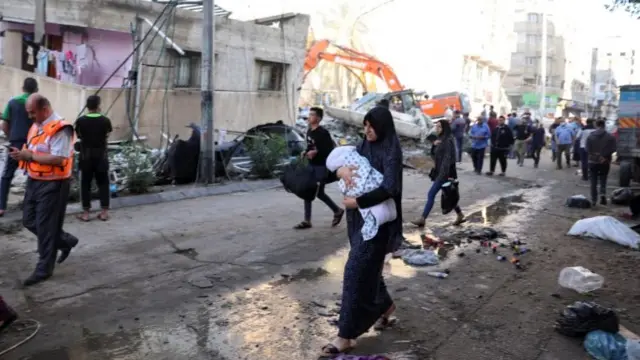 People walk past debris in a street at the site of Israeli air strikes, in Gaza City May 16, 2021