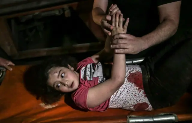 Palestinians carry a wounded girl after an Israeli air strike in Gaza City, 16 May 2021.