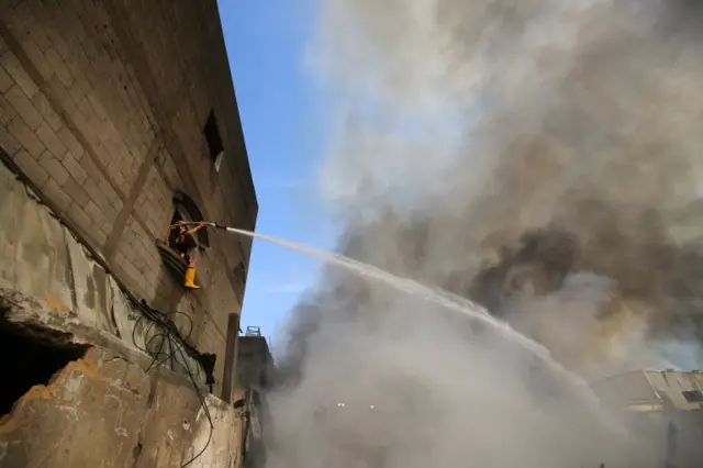 A Palestinian firefighter puts out a fire at a sponge factory after it was hit by Israeli artillery shells, according to witnesses, in the northern Gaza Strip May 17, 2021.