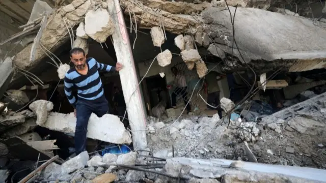 A Palestinian man walks through the ruins of a building destroyed in an Israeli air strike in Gaza (17 May 2021)