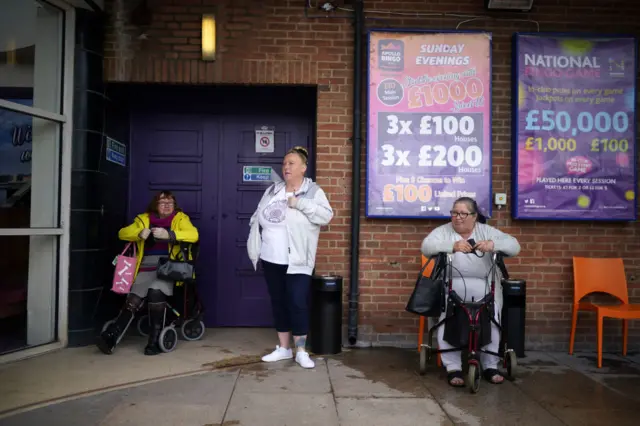 Women wait for the doors to open as they return to the bingo in Rhyl, Denbighshire