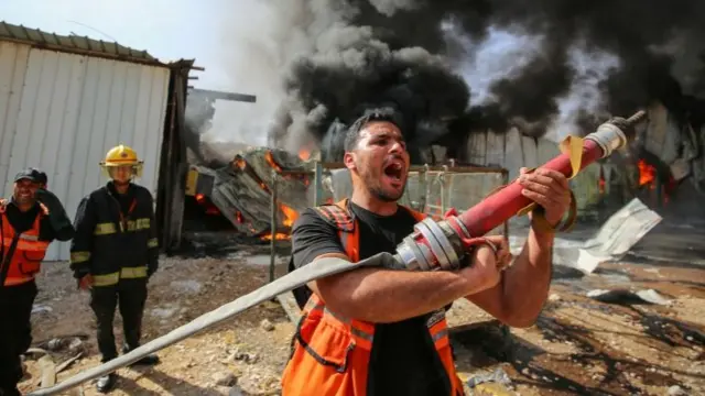 A Palestinian firefighter reacts as he participates in efforts to put out a fire at a sponge factory