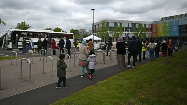 People queue for vaccinations from a centre set up in a bus in Bolton