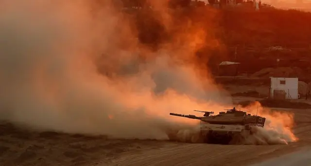 An Israeli Merkava tank rolls back from the Gaza Strip to an army base at the Israeli-Gaza border as the sun sets on August 3, 2014