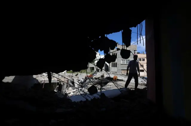 A Palestinian man is seen through the ruins in the aftermath of Israeli air strikes, in Gaza City May 17, 2021. REUTERS/Mohammed Salem