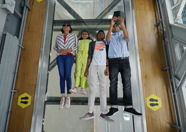 Visitors on the Glass Floor on the high-level walkway at Tower Bridge in London.