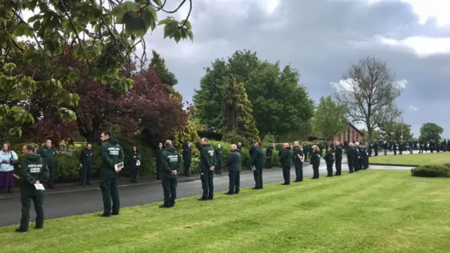 Ambulance staff standing beside route to crematorium