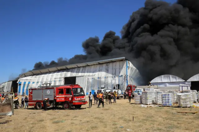 Firefighters try to extinguish a fire at a paint warehouse in Rafah, Gaza