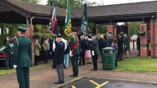 Ambulance staff with flags standing beside route to crematorium