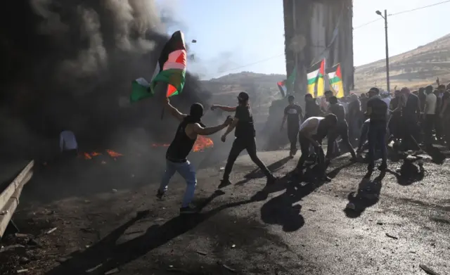 Palestinian protesters throw stones during clashes with Israeli troops