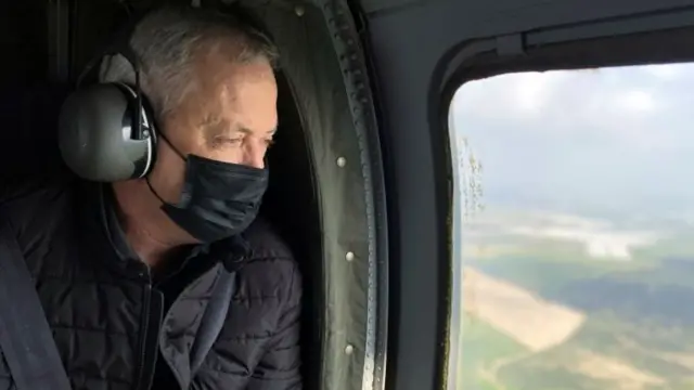 Israeli Defence Minister Benny Gantz wears a face mask as he looks out from the window of a helicopter during a tour of the Gaza border area in southern Israel