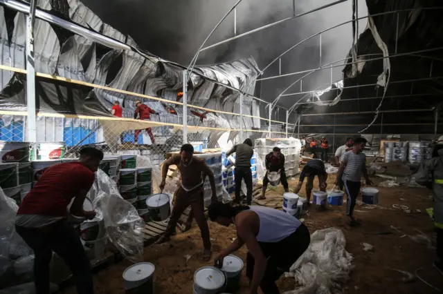 Firefighters try to extinguish a fire at a paint warehouse in Rafah, Gaza