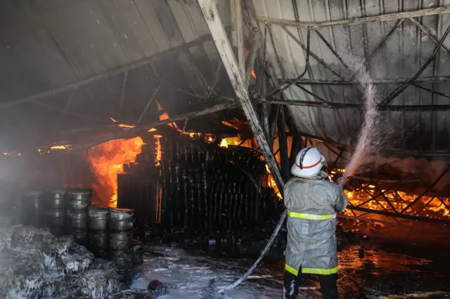 Firefighters try to extinguish a blaze at a paint warehouse in Rafah, Gaza