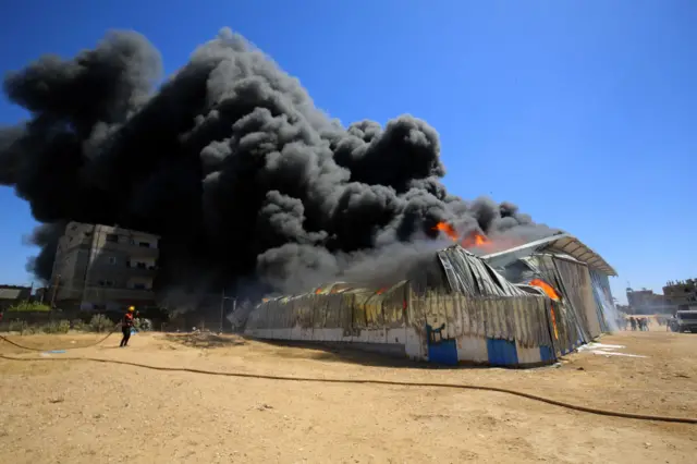 Firefighters try to extinguish a fire that broke out at a paint warehouse in Rafah